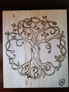 a wooden cutting board with an image of a tree and two faces carved into it