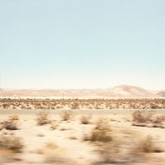 a train traveling through the desert with mountains in the background