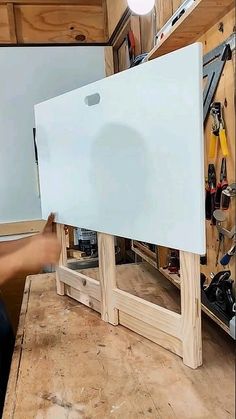 a person holding up a white board on top of a workbench