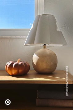 a lamp sitting on top of a wooden table next to a pumpkin