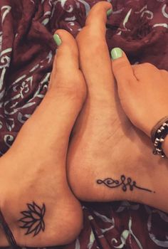 two women with matching tattoos on their feet are laying next to each other in bed