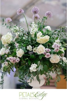 a vase filled with lots of white and purple flowers