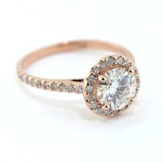 a rose gold engagement ring with a round diamond center and pave set diamonds around the band