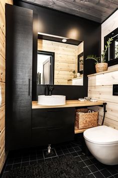 a black and white bathroom with wood paneling on the walls, toilet and sink