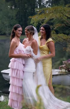 three beautiful women standing next to each other in front of a body of water and trees