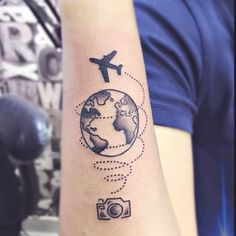 a person with a tattoo on their arm that has an airplane flying over the earth