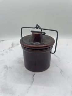 a brown pot sitting on top of a white counter next to a black wire holder