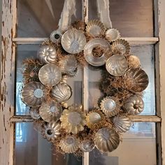 a wreath hanging on the front door of an old house with shells and seaweed