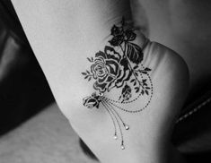 black and white photo of a woman's foot with tattoos on it, including roses