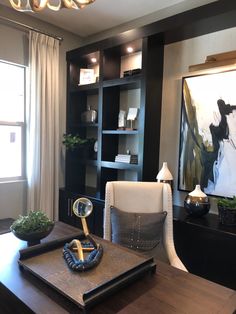 a room with a desk, chair and bookcases in front of a window