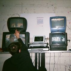 a man standing in front of two televisions on top of a table next to each other