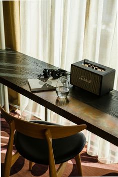 a wooden table topped with a radio next to a chair