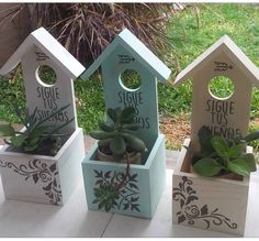 three wooden birdhouses with plants in them