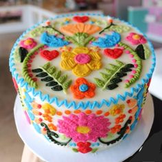 a decorated cake sitting on top of a white plate covered in frosting and colorful decorations