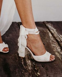 a close up of a person wearing high heeled shoes with flowers on the side