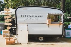 an old camper is parked in front of some boxes and signs that read caravan made