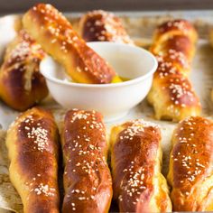 hotdogs and dipping sauce on a tray with breadsticks in the background