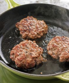 three hamburger patties cooking in a frying pan