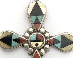 Acclaimed Zuni jewelers Zeno and Mary Ann Edaakie handcrafted this sterling silver and mosaic inlay cross with Sleeping Beauty turquoise, yellow mother of pearl, coral and jet. A Zuni Sunface is at the center of the cross. It hangs on a 26-inch chain. The back is signed ZME ZUNI NM. A word about inlay jewelry: It is best to remove inlay jewelry before bathing or showering. Do not wear inlay jewelry in hot tubs or pools. Avoid lotions, chemicals and prolonged exposure to water. The cross without Southwestern Silver Cross Jewelry, Handmade Southwestern Cross Pendant Jewelry, Handmade Southwestern Style Cross Pendant Jewelry, Multicolor Spiritual Jewelry With Inlay, Handmade Multicolor Cross Jewelry, Spiritual Multicolor Inlay Jewelry, Artisan Cross Jewelry For Jewelry Making, Collectible Large Cross Pendant Jewelry, Handmade Cross Jewelry Collectible