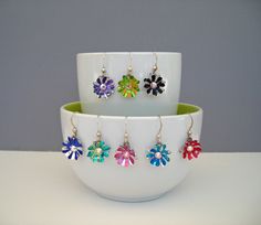 four flower shaped earrings sitting on top of a white bowl