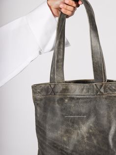 Transport your essentials with the Simple Tote Bag in Black by MM6 Maison Margiela. Crafted from high-quality calf leather, this tote features a unique faded effect and the brand's distinctive signature numbers motif and single-stitch logo. With a spacious main compartment and internal slip pocket, fully lined. Distressed Brown Waxed Finish Bag For Daily Use, Distressed Brown Waxed Bags For Daily Use, Luxury Oiled Leather Bag For Everyday Use, Distressed Brown Oiled Leather Bag For Daily Use, Vintage Vegetable Tanned Leather Bags For Daily Use, Oiled Leather Tote Bag With Leather Lining, Tote Bag With Leather Handles In Oiled Leather, Waxed Oiled Leather Tote Bag, Waxed Finish Oiled Leather Tote Bag