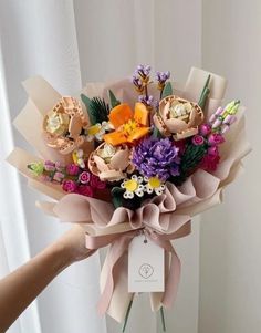 a person holding a bouquet of flowers in front of a white curtain with a tag on it