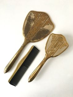 "3 piece vintage vanity set- long handled mirror, brush & comb Gold tone with floral/swirl pattern Comb is marked USA- I don't think comb was originally part of the set but it coordinates well Metal edge on comb is not secure and needs to be re-glued Brush head is removable for cleaning Items have been lightly cleaned but have not tried to clean brush bristles Mirror 13 1/2\" long about 5 1/2\" wide at widest point Brush 10\" long about 3 3/4\" wide at widest point Comb 8\" long x 2\" wide disco Bath Vanity Decor, Vanity Sets, Table Vanity, Dressing Table Vanity, Cleaning Items, Vanity Decor, Vanity Stool, Hand Mirror, Vintage Vanity