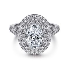 an oval cut diamond surrounded by halos and pave set diamonds in white gold