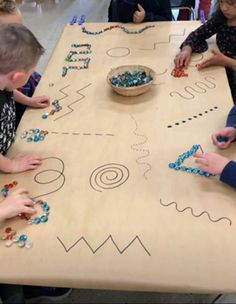 children are playing with beads on a table