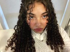 a woman with long curly hair is looking at the camera