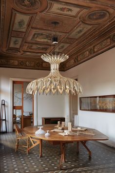 a chandelier hangs from the ceiling above a dining table in an ornately decorated room