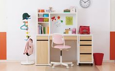 a pink chair sits in front of a small desk with a clock on the wall