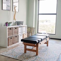 a living room with a large window and a bench in the middle of the room