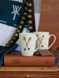 two coffee mugs sitting on top of a book next to a pair of glasses