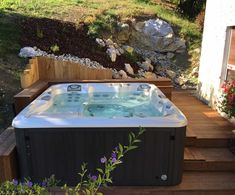 a hot tub sitting on top of a wooden deck next to a flower potted plant