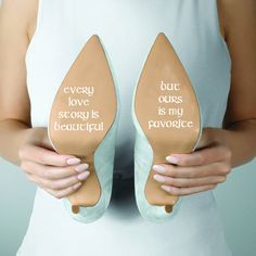 a woman holding two pairs of shoes with words on them