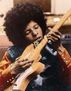 a man with an afro playing a guitar