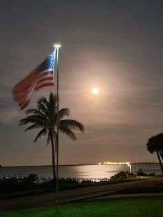 an american flag flying in front of the ocean at night