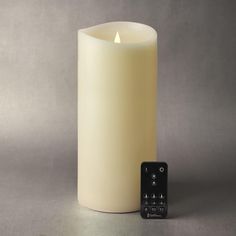 a lit candle next to a remote control