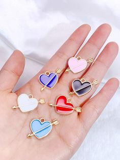 four heart shaped pins in different colors on a person's hand