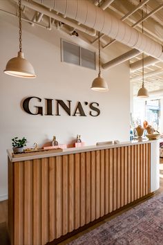 the front desk of gina's restaurant with hanging lights above it and an area rug on the floor