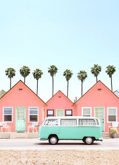 a blue and white van parked in front of pink houses with palm trees on the beach