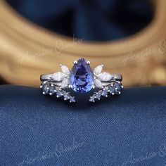 a tan and white diamond ring with blue sapphires on the side, sitting on top of a blue cloth