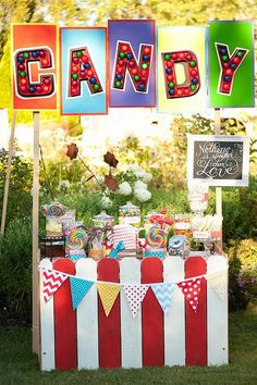 an outdoor candy bar is decorated with colorful paper letters and buntings that spell out the word candy