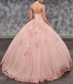 a woman in a pink ball gown with flowers on the skirt is looking back at the camera