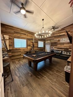 a pool table in the middle of a room with wood paneling on the walls