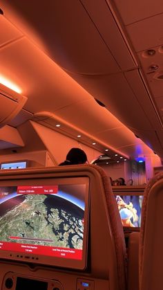 the inside of an airplane with people watching television