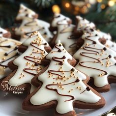 christmas cookies decorated with white and brown icing on a plate next to a christmas tree