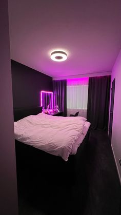 a large bed sitting in a bedroom under a purple light