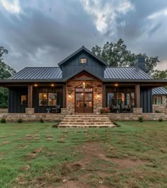 a house with a metal roof and stone steps leading up to the front door on a grassy lawn